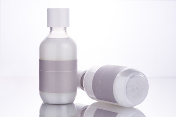 Two translucent cosmetic bottles with a milky white toner liquid inside