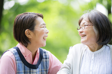 Obraz premium 新緑の中散歩をする介護士と高齢者の見つめ合う笑顔のクローズアップ