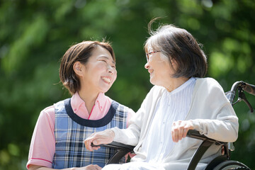 Close-up of a caregiver and an elderly person looking at each other and smiling as they take a walk...