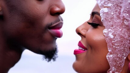Close-up video, frosted pink lips, passionate kiss between dark-skinned man (soft pink) & light-skinned woman (icy pink), high contrast enhances texture Concept of intimacy and desire