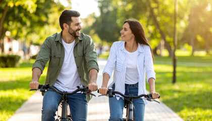 Fototapeta premium Happy couple enjoying a sunny day while riding bicycles in the park