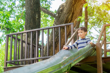Obraz premium Little asian boy playing purple slider and happy fun or cheerful enjoy on holiday. kid at the playground. Background. Copy space. Learning Concept.