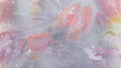 abstract art with deep frozen tulip flowers in ice, water and milk resulting in a watercolor paint like background in soft pastel colors