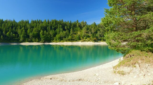Clear turquoise lake Urisee in the Austrian Alps with peaceful shoreline, green hills, and summer sunlight near Reutte Tirol