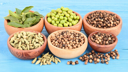 Fototapeta premium Assorted spices in wooden bowls on blue background; culinary, food photography, recipe ingredient