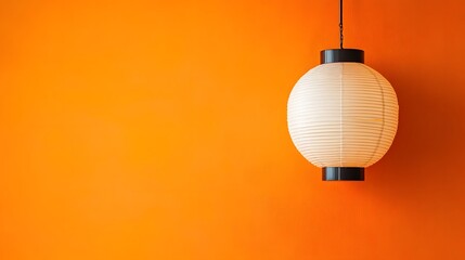 Vintage Japanese paper lantern hanging against a vibrant orange backdrop