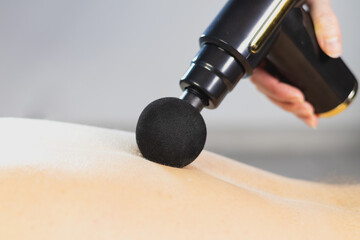 Woman doing massage on mans back with percussion massage gun for vertebrae relax and recovery....