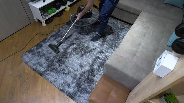 Professional cleaner vacuums a shaggy rug in an apartment with a brush with fast speeds, cleaning fabric furniture, cleaning an apartment with a vacuum cleaner. Slow motion