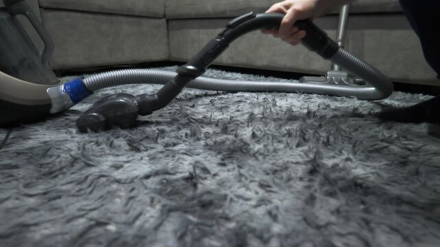  Close-up. Vacuum cleaner cleaning a pile rug from dirt with a special brush at high speed. Cleaning furniture with a vacuum cleaner. Slow motion