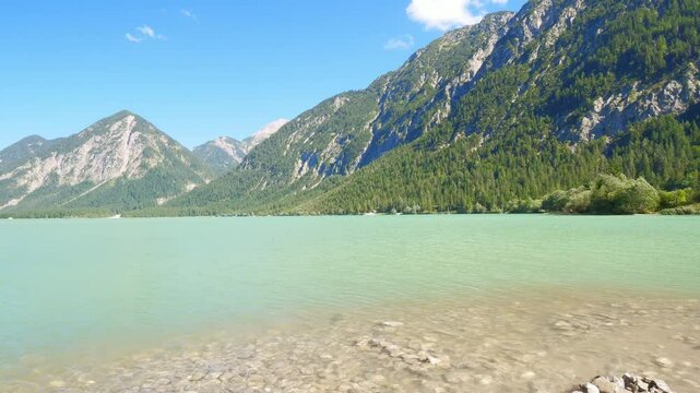 Heiterwanger See with crystal clear water and alpine backdrop in Tirol, surrounded by lush hills and peaceful lakeside atmosphere