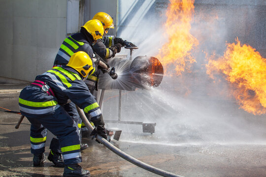 Firefighters work together using water hose to extinguish a dangerous fire during a gas leak training drill