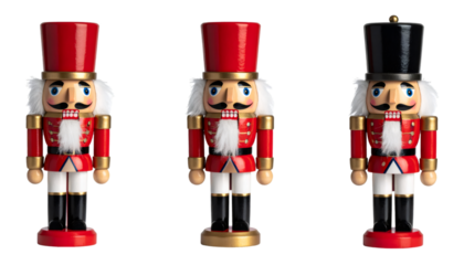 Wooden Christmas nutcrackers wearing red uniforms, white pants, black boots, standing together against transparent backdrop