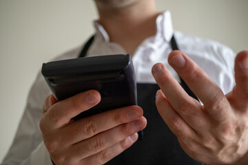 Close-up man in waiter apron holding pos machine