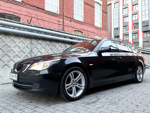 Black BMW E61 5-series parked in the city street. Exterior Germany black BMW 5 series E61 station wagon parked in the center of the town. Germany premium car. 