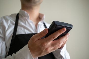 Close-up man in waiter apron holding pos machine
