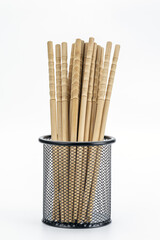 Chopsticks in Holder:  A collection of bamboo chopsticks in a black wire mesh holder, a simple arrangement. Highlighting the everyday elegance and minimalist design. 