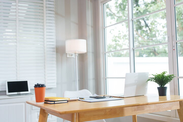 A casually dressed Asian businesswoman works from home while meeting online with a client, looking relaxed, focused and professional despite the informal setting.