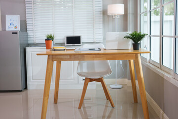 A casually dressed Asian businesswoman works from home while meeting online with a client, looking relaxed, focused and professional despite the informal setting.