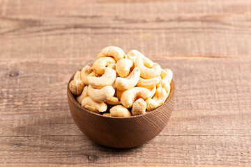 Organic roasted cashew nuts in a wooden bowl. Top view. 