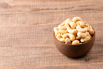 Organic roasted cashew nuts in a wooden bowl. Top view. 