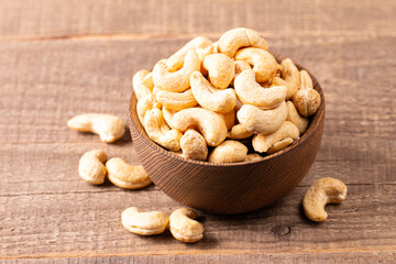 Organic roasted cashew nuts in a wooden bowl. Top view. 