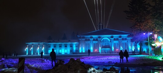 A tall building stands illuminated with vibrant blue lights during the night © CRUSH