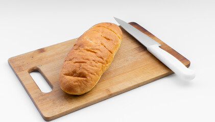 Freshly baked loaf of bread on a wooden cutting board with a white knife at a kitchen countertop