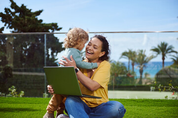 Mother and Child Bonding Outside with Laptop and Scenic View