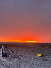 Snowy Airport Runway at Red Sunrise with Distant Plane. Bright red sunrise over a snowy airport...