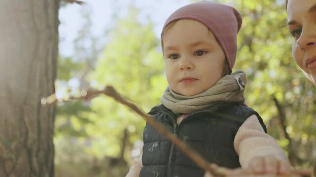 Mom and daughter have a great time walking through the woods and exploring a grasshopper on a stick, warm autumn time with famil