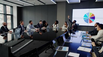 A high-angle video shot of a modern conference room with diverse professionals engaged in a meeting, laptops open, and cityscape views. - Powered by Adobe