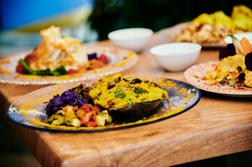 A plate of food with a yellow sauce on it. The plate is on a wooden table. There are other plates of food on the table as well