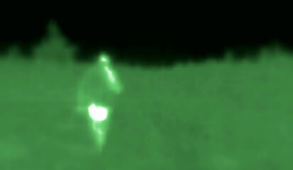 The man is going by park road. Image from thermal imager device. Medium infrared spectrum