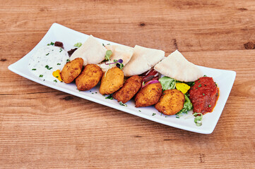 A plate of food with a variety of items including a few pieces of chicken, a few pieces of bread, and a few pieces of vegetables