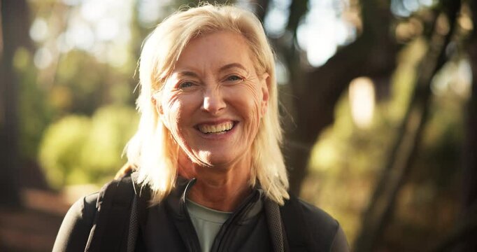 Hiking, mature woman and face in woods for adventure, retirement hobby and cardio wellness. Senior person, smile and portrait with backpack for trekking, explore and holiday sightseeing in forest