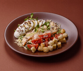 Bowl with caesar salad with chicken, parmesan cheese, tomatoes, croutons, lettuce leaves