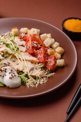 Bowl with caesar salad with chicken, parmesan cheese, tomatoes, croutons, lettuce leaves