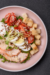 Bowl with caesar salad with chicken, parmesan cheese, tomatoes, croutons, lettuce leaves