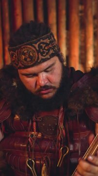 Musician with overweight plays bow instrument during performance in traditional living cabin closeup. Ceremonial sounds of Altai shamans
