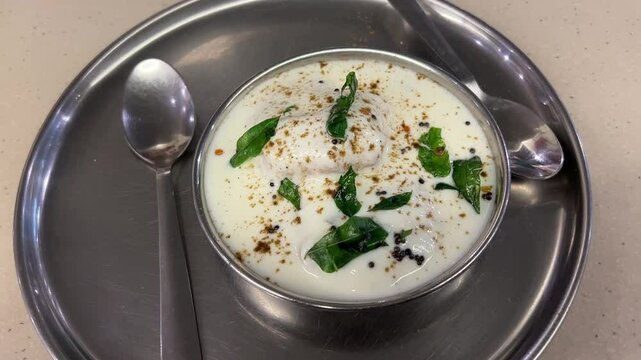 Home made dahi vada served with curry leaves in a steel plate in India.