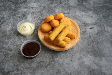 A plate of fried chicken fingers and a side of dipping sauce. The dipping sauce is in a plastic...