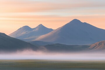 Fototapeta premium Misty sunrise over volcanic peaks. A tranquil landscape of misty mountains. Soft light paints the peaks, while a light mist hangs low over the valleys
