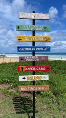 Welcome sign to Goat's Beach (Praia do Bode). Fernando de Noronha, Brazil. No wifi. Portuguese language signs. Multicolored signs. Arrows pointing to the direction of nearby beaches. Peace sign.