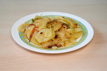 A plate of food with potatoes and carrots on it. The plate is white and blue. The food is on a wooden table