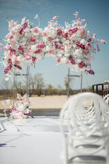 Rectangular arch for a wedding ceremony by the river. White chairs for guests. Outdoor ceremony