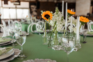 Wedding banquet hall decor with round green tables, white roses and sunflowers on the tables