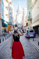 Young woman in hat enjoying the view of Galata tower, Istanbul, Turkey