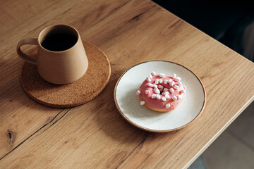 Appetizing pink donut on the kitchen table, decorated with marshmallows.