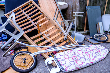 Discarded furniture and debris cluttering a vacant lot in an urban area during daylight hours