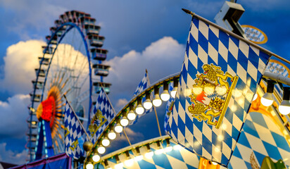 Ferris wheel illuminated at dusk with vibrant colors against a cloudy sky in a festive atmosphere